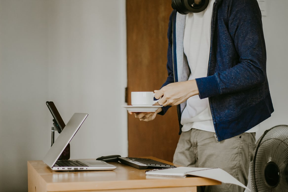 Man with Cup of Drink at the Table with Laptop